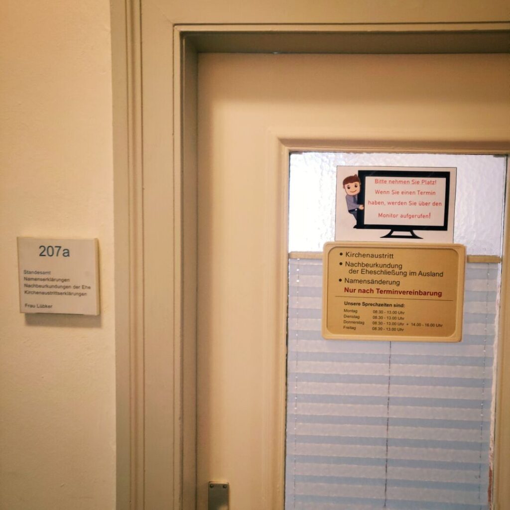 Die Tür zu Raum 207a zeigt ein Schild mit Informationen zu Standesamt-Dienstleistungen, einschließlich Namensänderungen und Kirchenaustritten, sowie Hinweise zur Terminvereinbarung und Sprechzeiten.