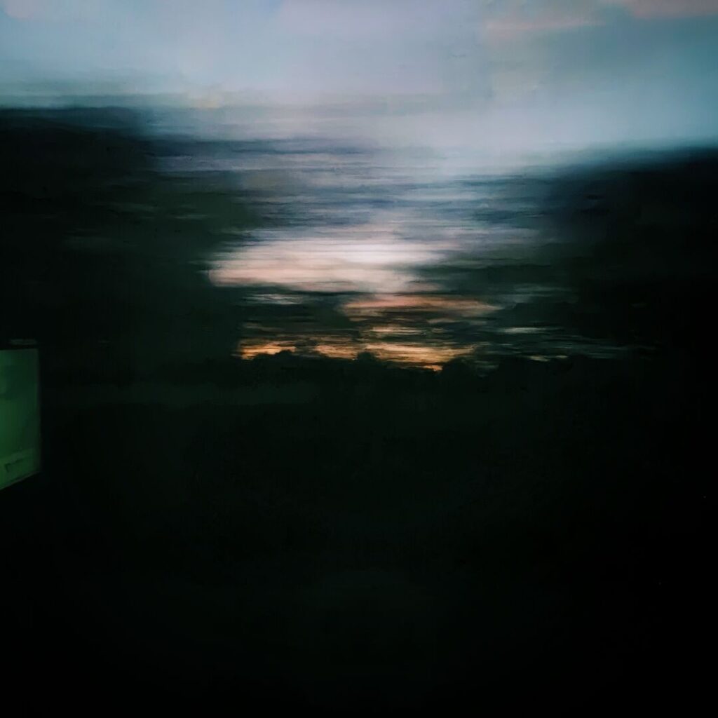 Ein verschwommenes, dunkles Landschaftsbild mit sanften Farbtönen von Blau und Orange, das den Übergang von Tag zu Nacht darstellt.