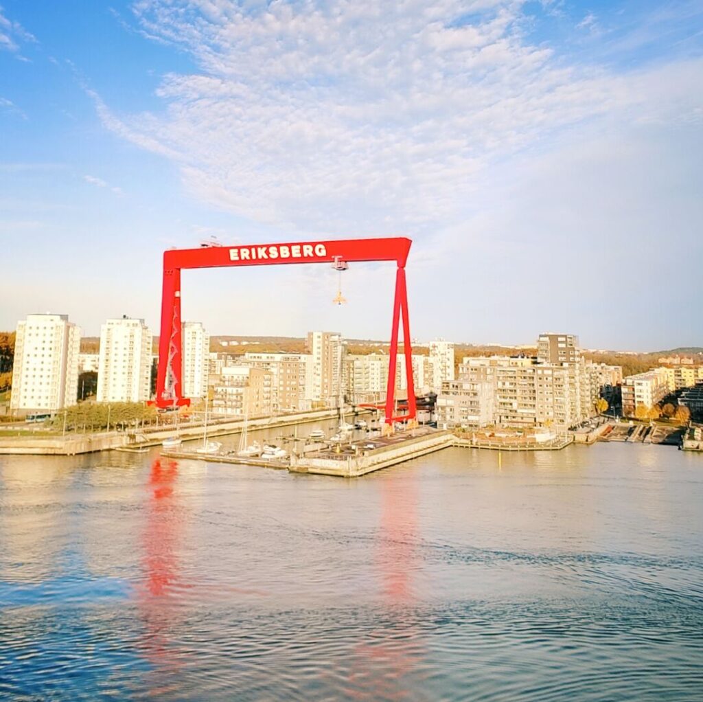 Roter Kran mit der Aufschrift "ERIKSBERG" über einer modernen Hafenlandschaft und Wohngebäuden am Wasser.