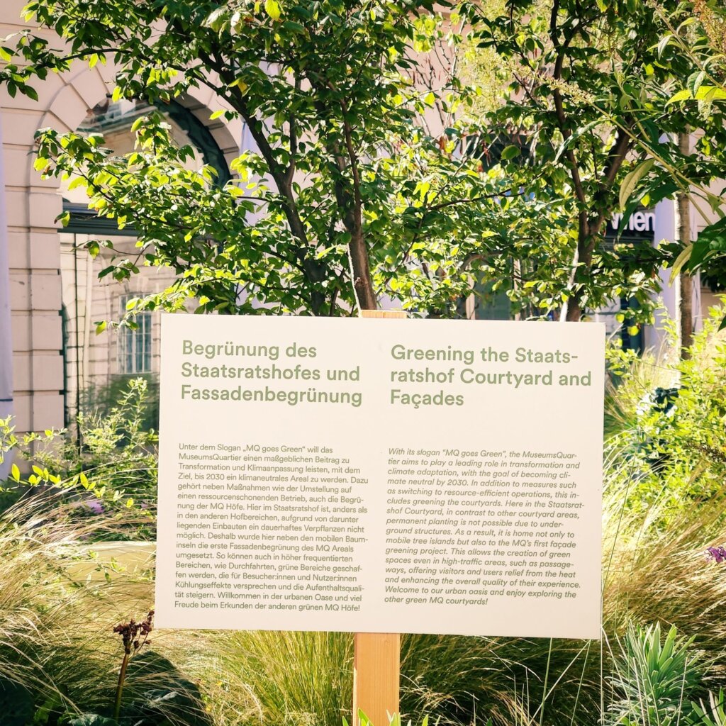 Informationstafel zur Begrünung des Staatsratshofes und der Fassaden im MuseumsQuartier, die Ziele und Maßnahmen zur Transformation und Klimaanpassung bis 2030 erläutert, um ein klimaneutrales Areal zu schaffen.